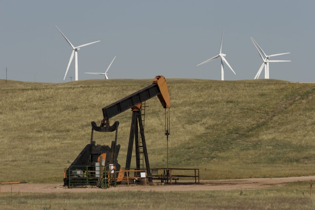 Windmills near pumpjacks in an oil field
