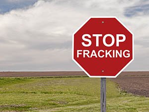 Image of grassy field with stop sign shape that has words Stop Fracking