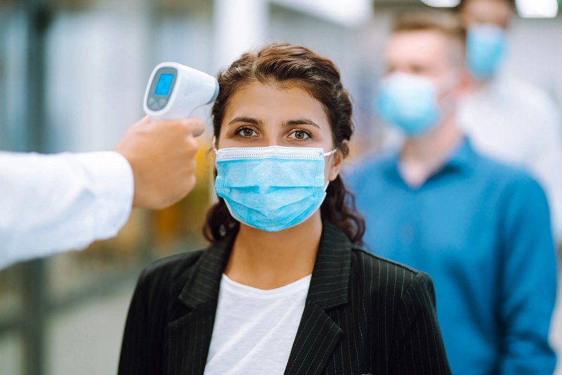 Image of person wearing face mask having temperature taken