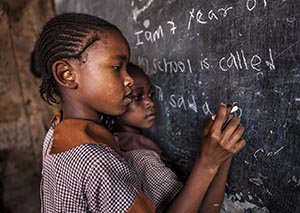 Young girls at an orphanage in Kenya learn is a classroom with no electricity