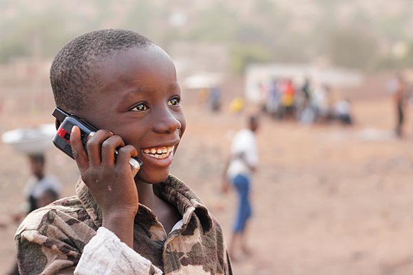 Image of smiling child in Africa talking on a mobile phone