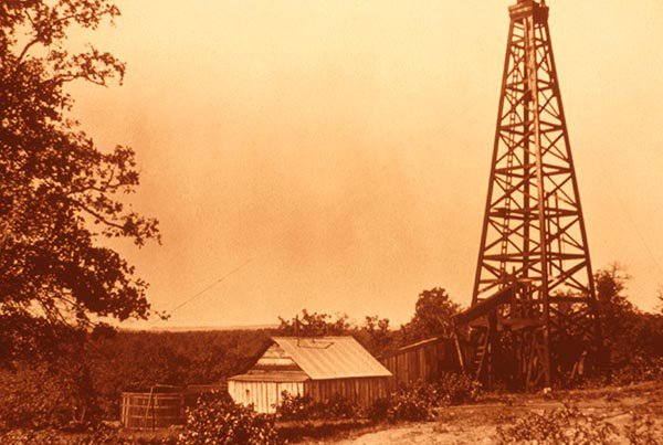 Image of a derrick and well site from the 1920s